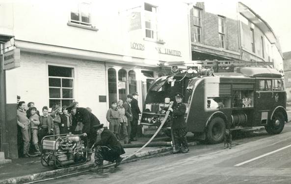 The fire brigade pump out a flooded cellar on High Street, Market Lavington in 1961