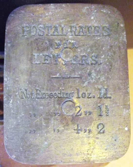 Postal charges (for 1880) are embossed on the scale pan
